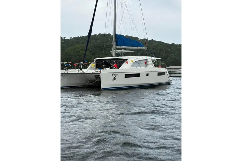 Sweet 2 Bad Yacht Photos Pics 2016 Leopard 404 catamaran anchored on water, surrounded by lush greenery.