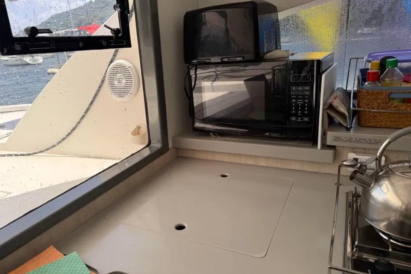 Sweet 2 Bad Yacht Photos Pics Compact kitchen area on a Leopard 404 yacht, featuring a microwave, kettle, and organized storage.