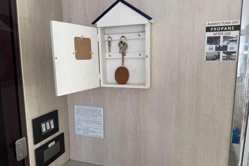 Sweet 2 Bad Yacht Photos Pics Key holder with keys, propane warning sign, and electrical switches on a wall.