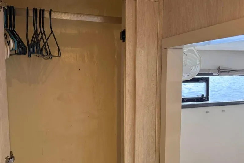 Sweet 2 Bad Yacht Photos Pics Empty wooden closet with hangers on a Leopard 404, 2016 model, near a window view.