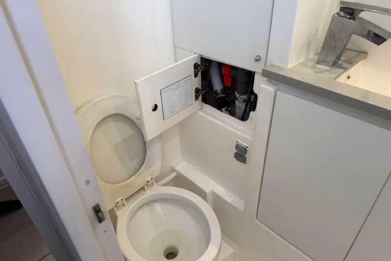 Sweet 2 Bad Yacht Photos Pics Compact bathroom with open toilet and plumbing access panel in a Leopard 404, 2016 model.