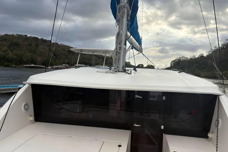 Sweet 2 Bad Yacht Photos Pics Sailing catamaran Leopard 404, 2016 model, docked by a scenic river under cloudy skies.