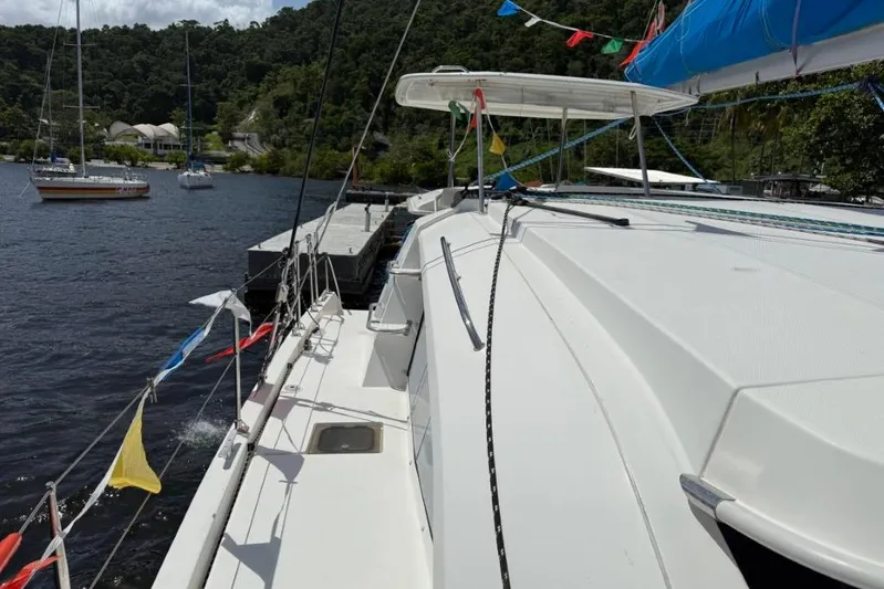 Sweet 2 Bad Yacht Photos Pics 2016 Leopard 404 catamaran docked, decorated with colorful flags, surrounded by lush greenery.