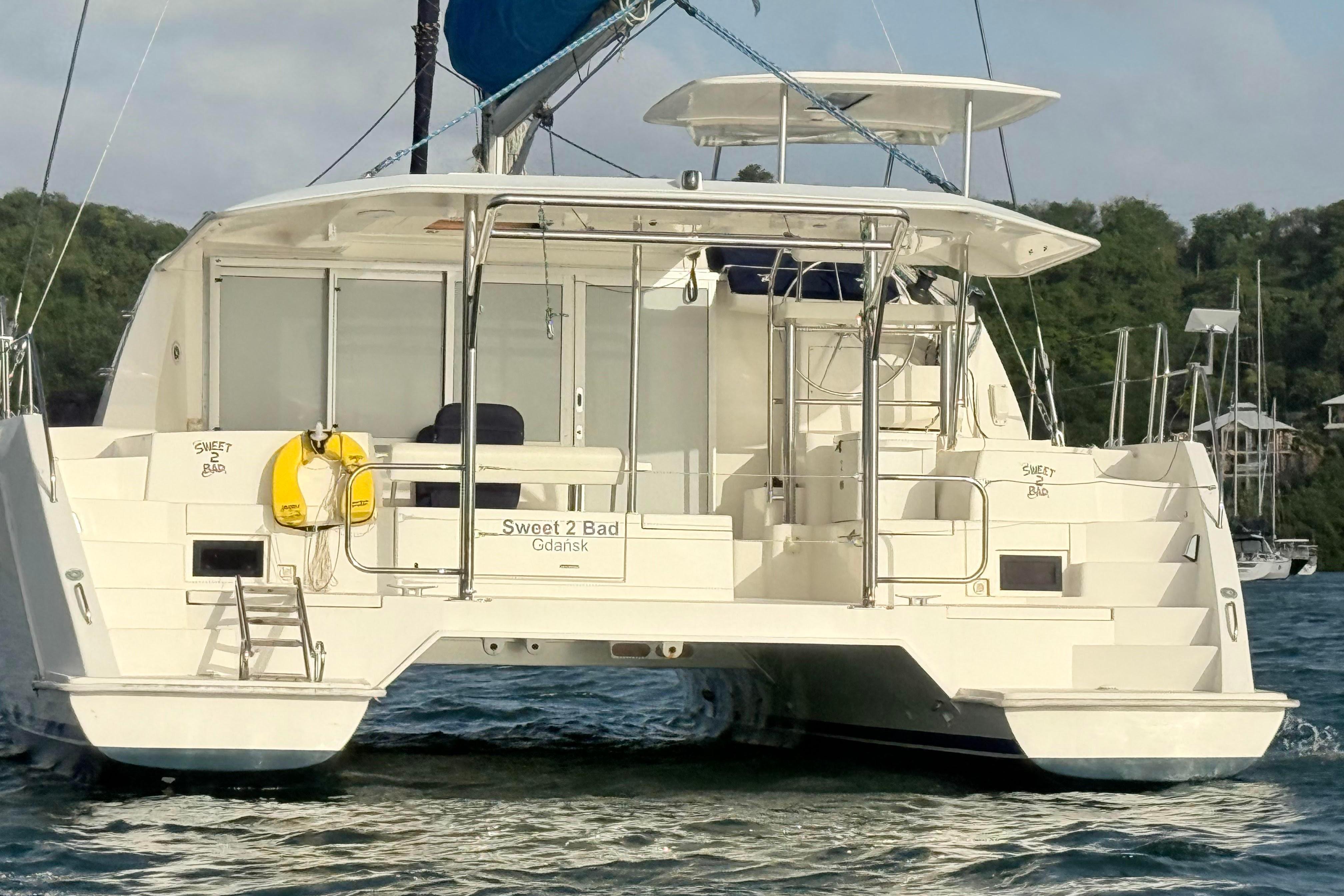 2017 Leopard 40 catamaran "Sweet 2 Bad" on water, rear view with lush background.