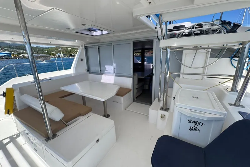 Sweet 2 Bad Yacht Photos Pics Spacious deck of 2017 Leopard 40 catamaran with seating and table, docked by the sea.