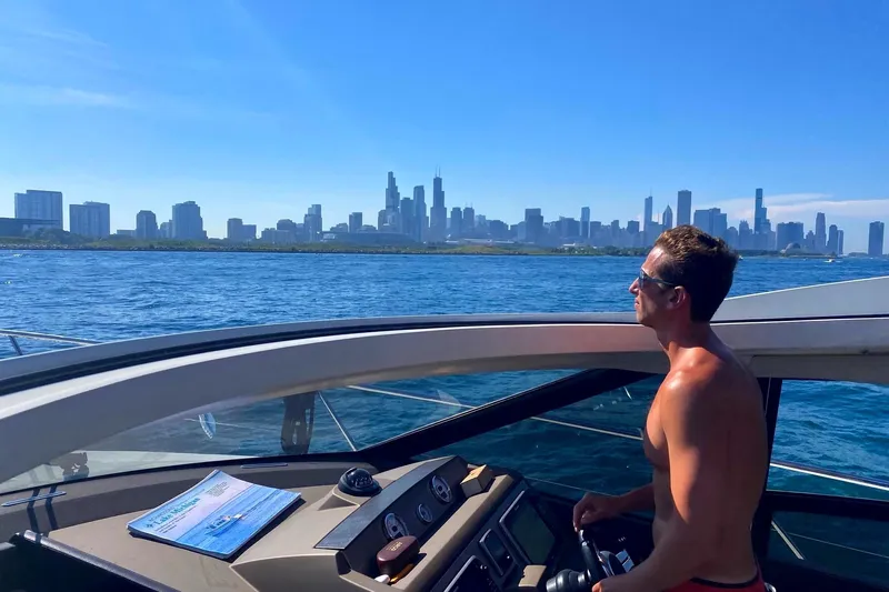 Top Nach Yacht Photos Pics Man steering 2017 Prestige 500S yacht with city skyline in background.