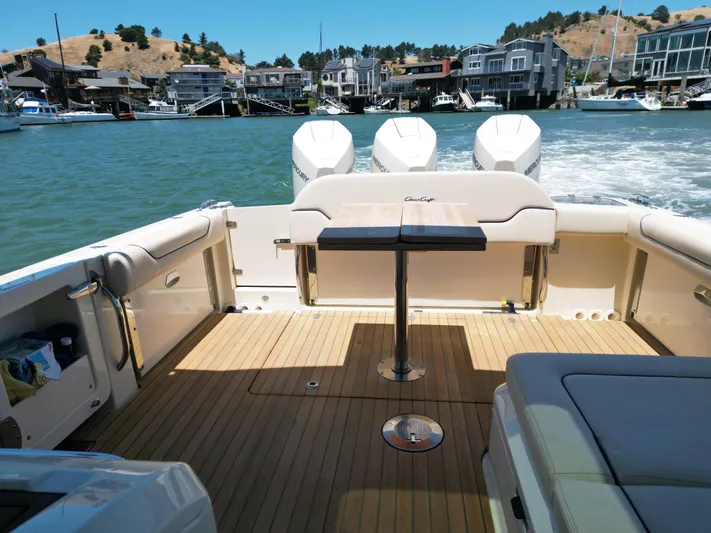 Sea Dragon Yacht Photos Pics 2023 Chris-Craft Calypso 35 boat interior with wooden deck and table, docked near waterfront homes.