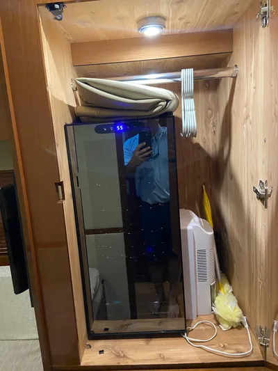 Yonder Star Yacht Photos Pics Wooden cabinet interior on a 2016 Sea Ray 510 Fly yacht, featuring a mirrored door and storage items.