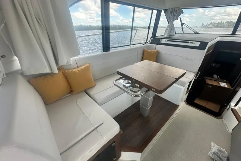  Yacht Photos Pics Interior of 2025 Beneteau Antares 12 yacht with cozy seating and wooden table.