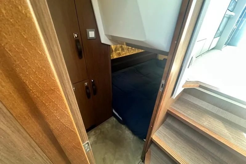  Yacht Photos Pics Cozy cabin interior of 2025 Beneteau Antares 12 with wooden finishes and blue bedding.