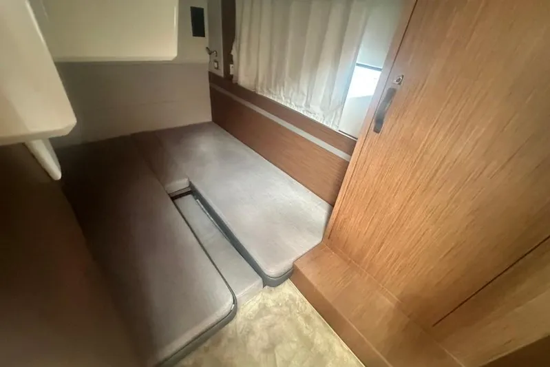  Yacht Photos Pics 2025 Beneteau Antares 12 cabin interior with wooden finish and cushioned seating.