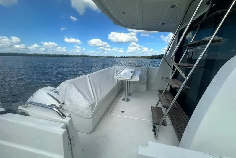  Yacht Photos Pics 2025 Beneteau Antares 12 yacht deck with seating and ladder, overlooking serene water.