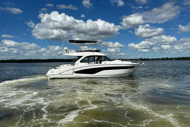  Yacht Photos Pics 2025 Beneteau Antares 12 yacht cruising on a sunny day with cloudy sky.