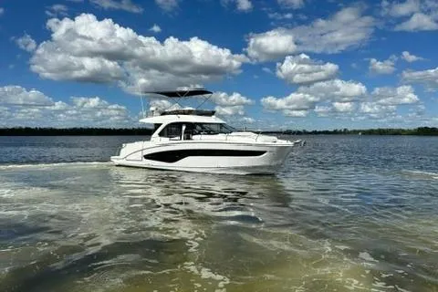 Yacht Photos Pics 2025 Beneteau Antares 12 yacht cruising on a sunny day with blue skies and clouds.