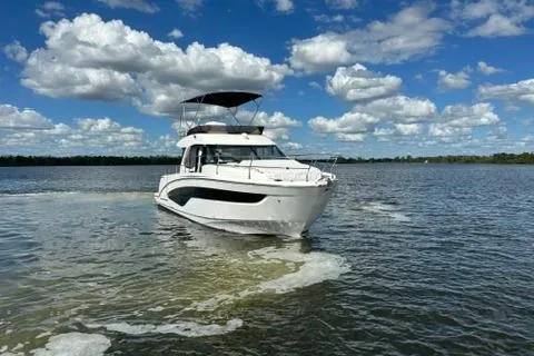  Yacht Photos Pics 2025 Beneteau Antares 12 cruising on a sunny day with blue skies and clouds.