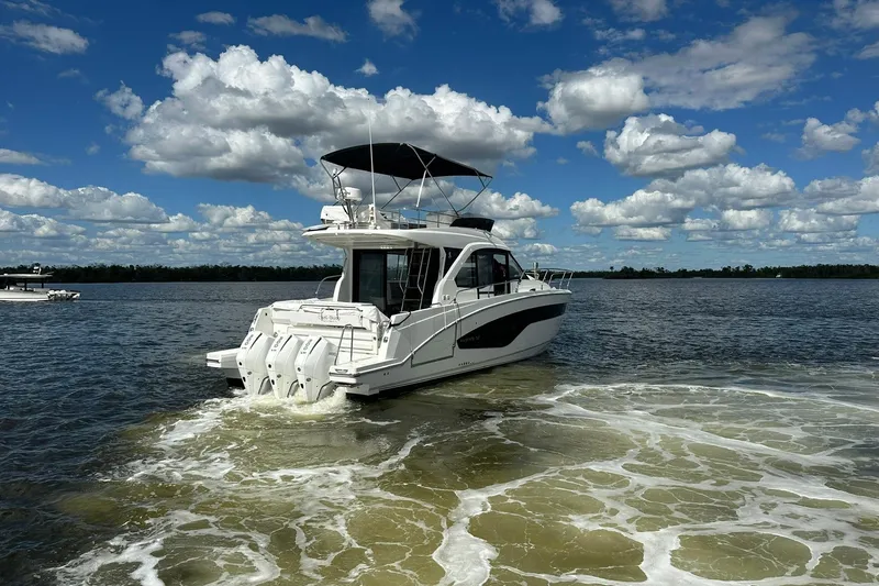  Yacht Photos Pics 2025 Beneteau Antares 12 cruising on a sunny day with scenic clouds.