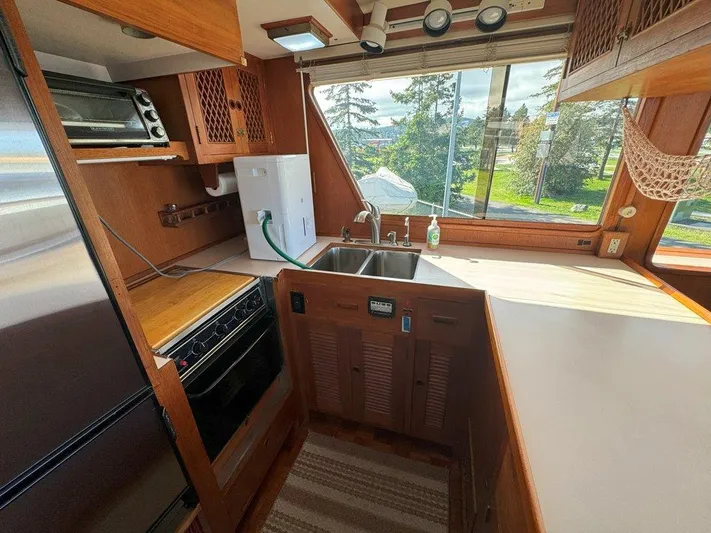  Yacht Photos Pics 1980 Ocean Alexander 50 MK1 yacht kitchen with wood cabinetry, sink, and large window view.