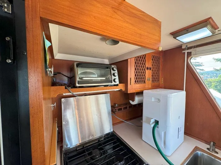  Yacht Photos Pics Galley kitchen in 1980 Ocean Alexander 50 MK1 yacht with appliances and wooden cabinetry.