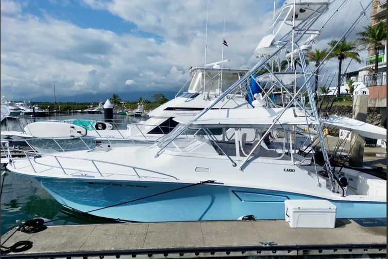  Yacht Photos Pics 2004 Cabo 40 Express Los Suenos yacht docked at marina under cloudy sky.