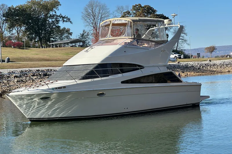  Yacht Photos Pics 2005 Carver 33 Super Sport yacht on calm water, surrounded by trees and clear sky.