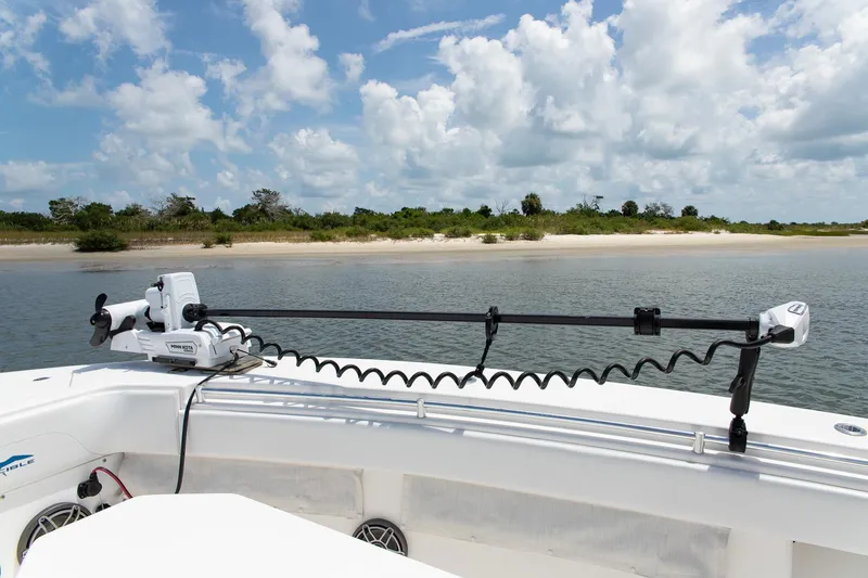  Yacht Photos Pics 2015 Invincible 36 Open Fisherman boat with trolling motor, near sandy shoreline under blue sky.