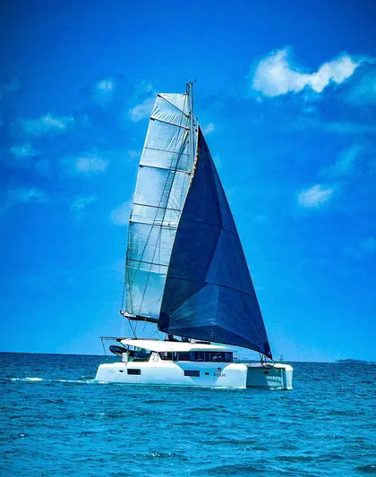 Roxie Yacht Photos Pics 2024 Lagoon 42 catamaran sailing on open sea under clear blue sky.