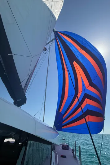 Roxie Yacht Photos Pics 2024 Lagoon 42 catamaran with vibrant blue and orange sail on open sea.