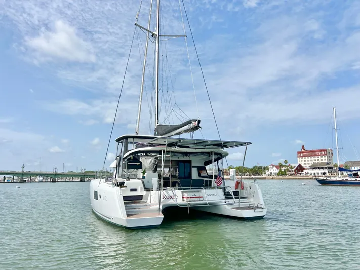 Roxie Yacht Photos Pics 2024 Lagoon 42 catamaran anchored in a scenic harbor with clear skies.
