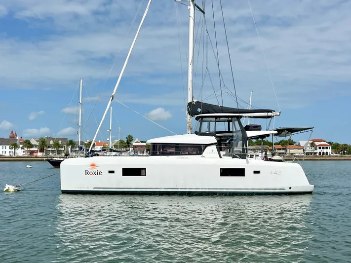 Roxie Yacht Photos Pics 2024 Lagoon 42 catamaran sailing on calm waters under a clear blue sky.
