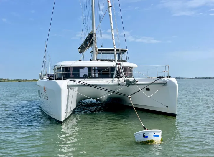 Roxie Yacht Photos Pics 2024 Lagoon 42 catamaran anchored in calm waters under a clear blue sky.
