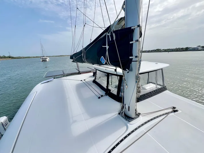 Roxie Yacht Photos Pics 2024 Lagoon 42 catamaran sailing on calm waters under a cloudy sky.