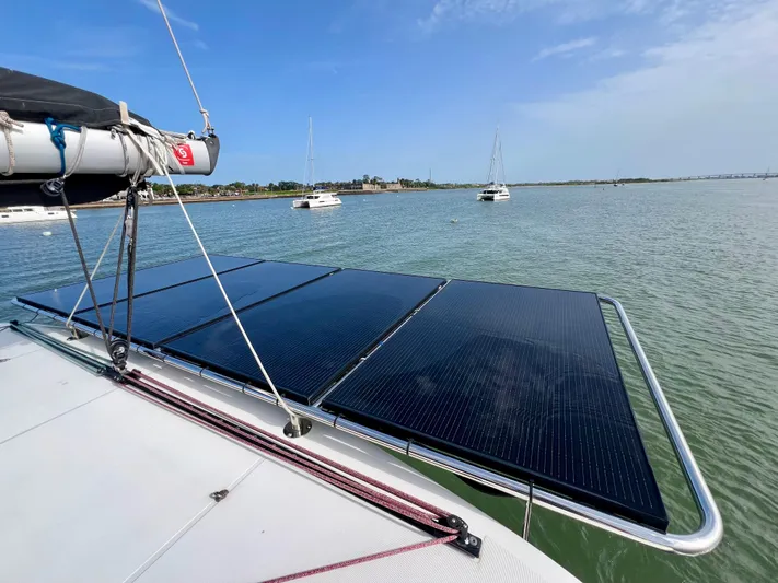 Roxie Yacht Photos Pics 2024 Lagoon 42 catamaran with solar panels on deck, anchored in calm waters.