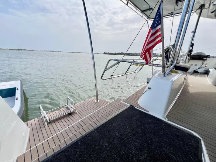 Roxie Yacht Photos Pics 2024 Lagoon 42 catamaran deck with American flag, overlooking calm waters.