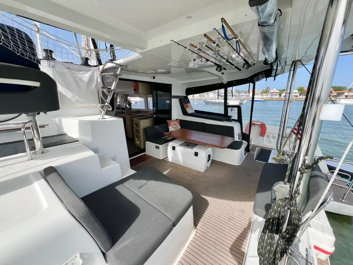 Roxie Yacht Photos Pics 2024 Lagoon 42 catamaran interior with modern seating, fishing rods, and waterfront view.