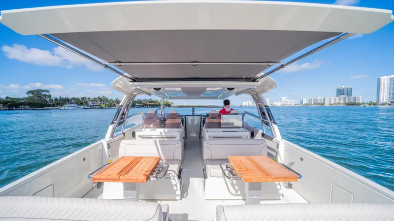  Yacht Photos Pics 2025 YOT 36 boat with open deck, wooden tables, and scenic waterfront view.