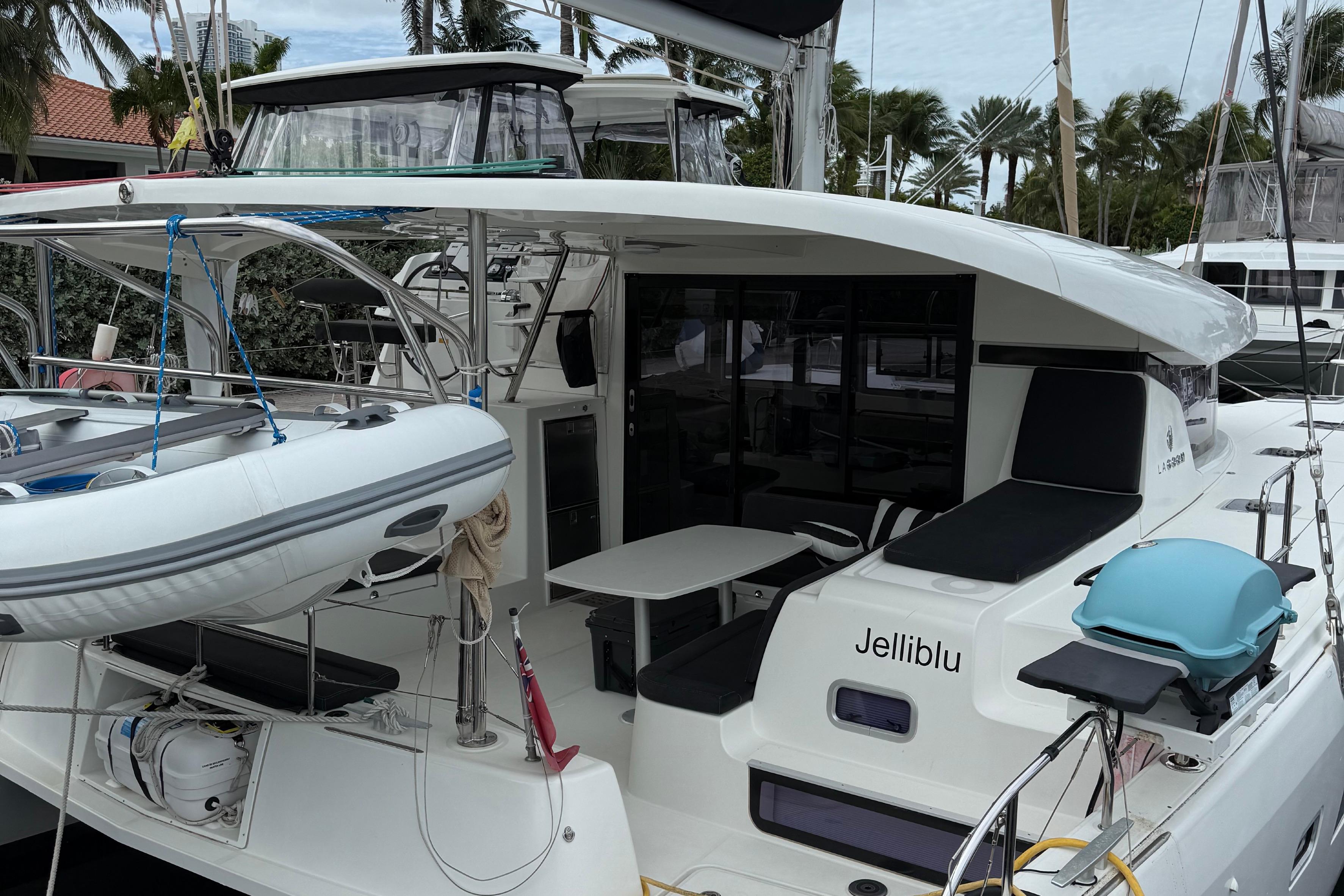 2019 Lagoon 42 catamaran docked, featuring outdoor seating and a small boat on deck.