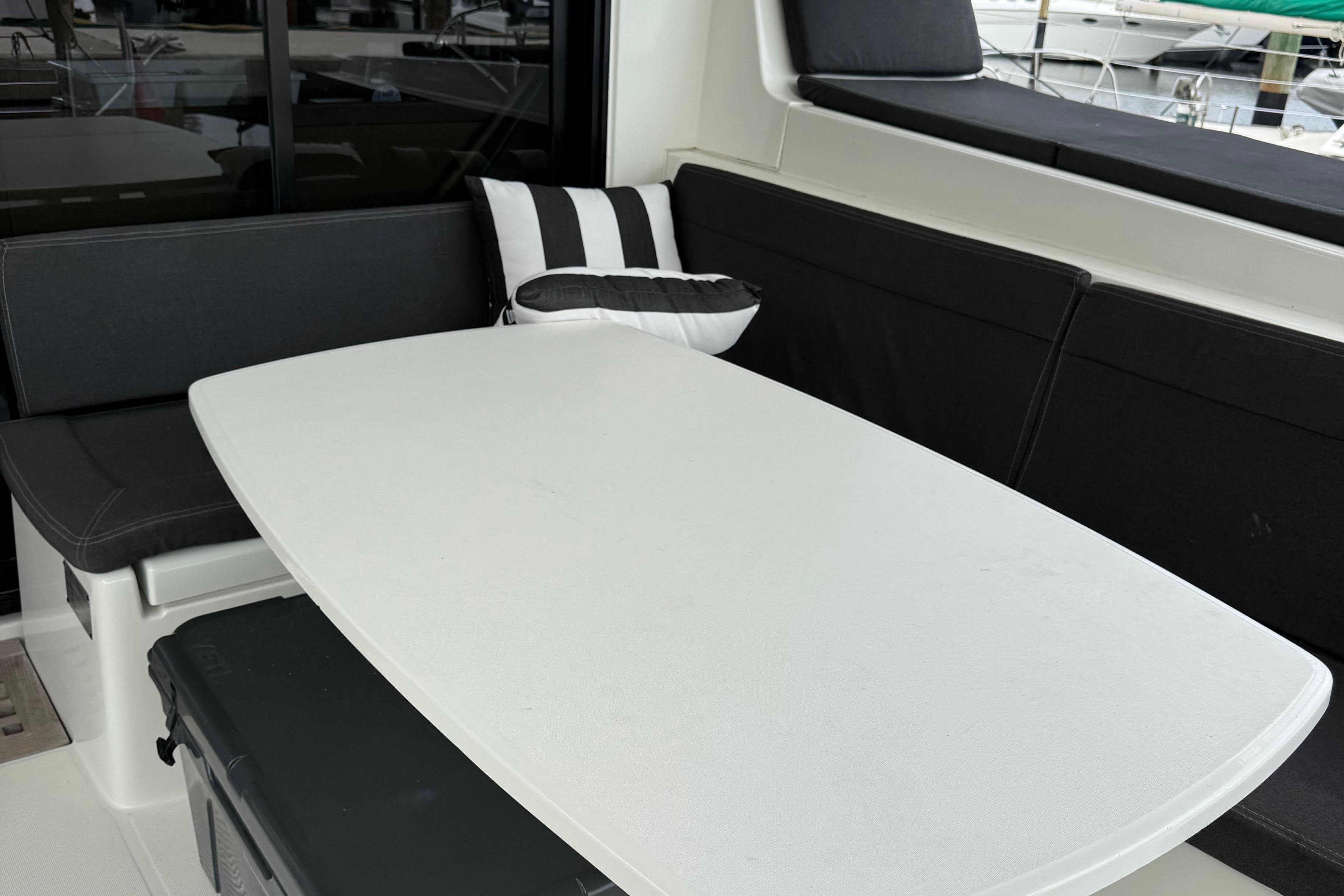 Cozy seating area on 2019 Lagoon 42 catamaran with black cushions and striped pillow.