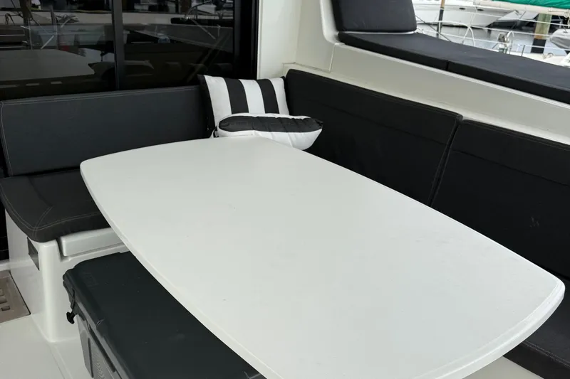 Jelliblu Yacht Photos Pics Cozy seating area on 2019 Lagoon 42 catamaran with black cushions and striped pillow.