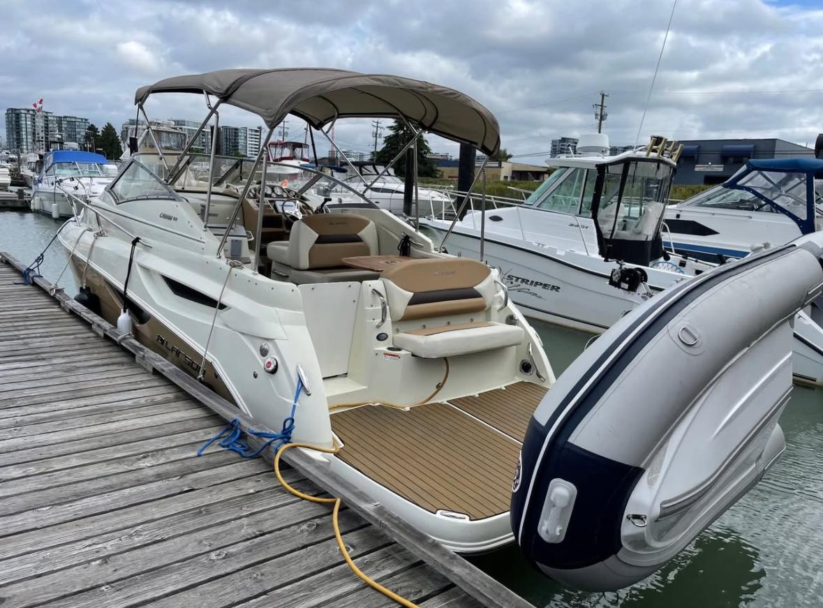 2014 Larson Cabrio 285 boat docked at marina, featuring spacious deck and canopy.