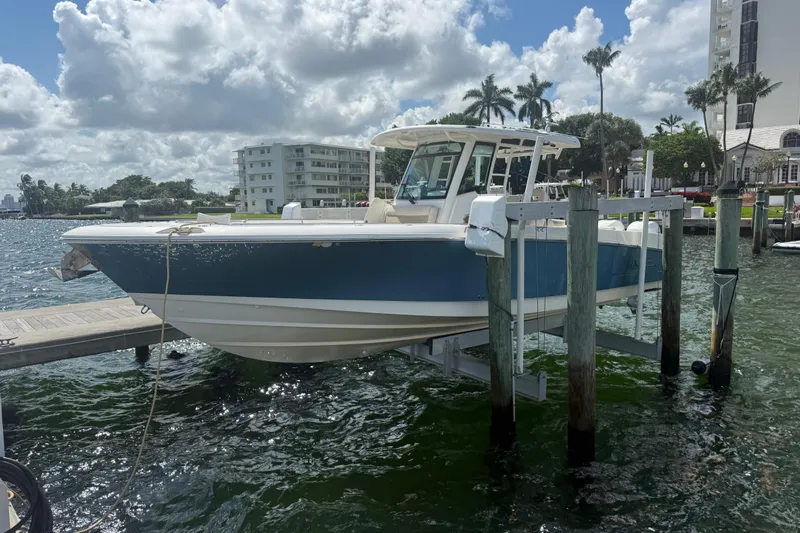 Dulce Vita Yacht Photos Pics 2016 Boston Whaler 330 Outrage boat docked on a lift, with scenic waterfront backdrop.