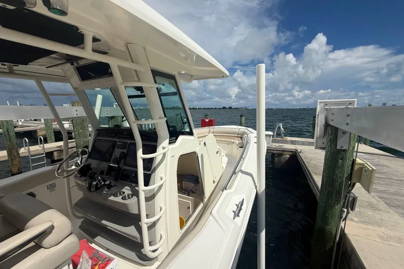 Dulce Vita Yacht Photos Pics 2016 Boston Whaler 330 Outrage docked, showcasing helm and seating, under a partly cloudy sky.