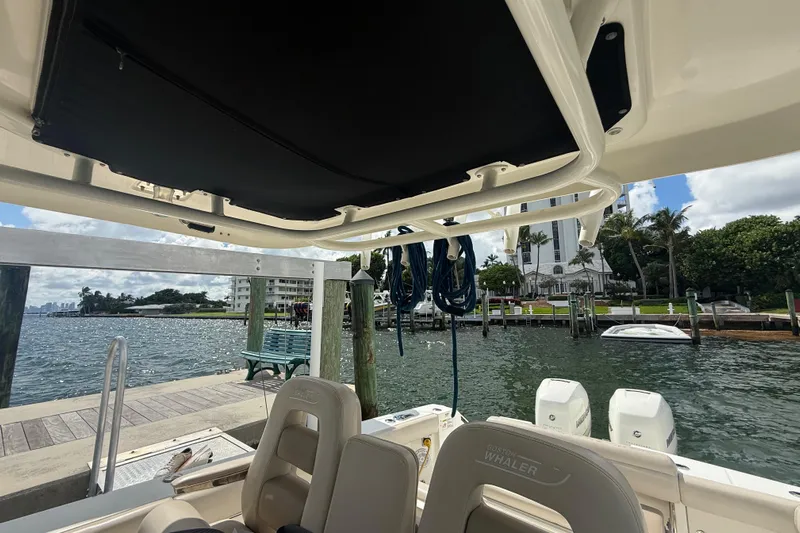 Dulce Vita Yacht Photos Pics 2016 Boston Whaler 330 Outrage at dock, scenic waterfront view, palm trees, and buildings.