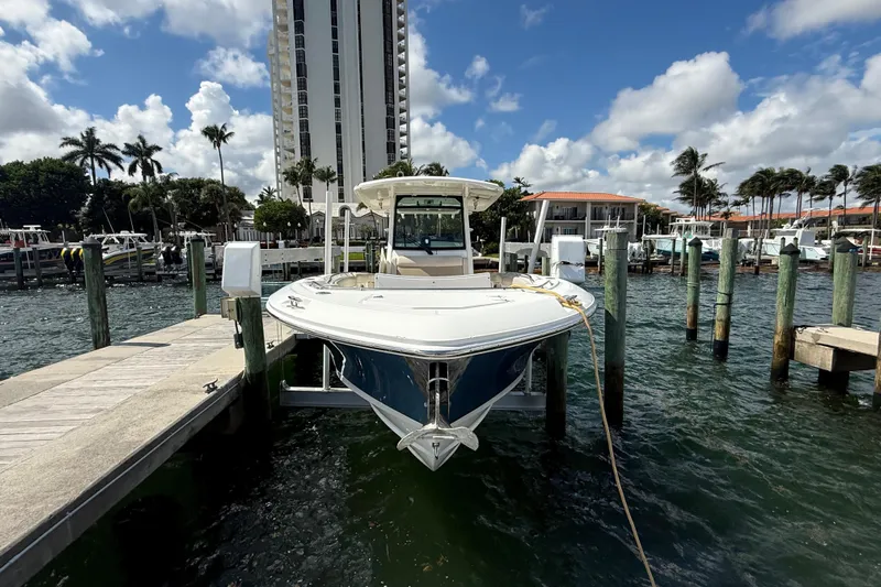 Dulce Vita Yacht Photos Pics 2016 Boston Whaler 330 Outrage docked at marina, with tall building and palm trees in background.