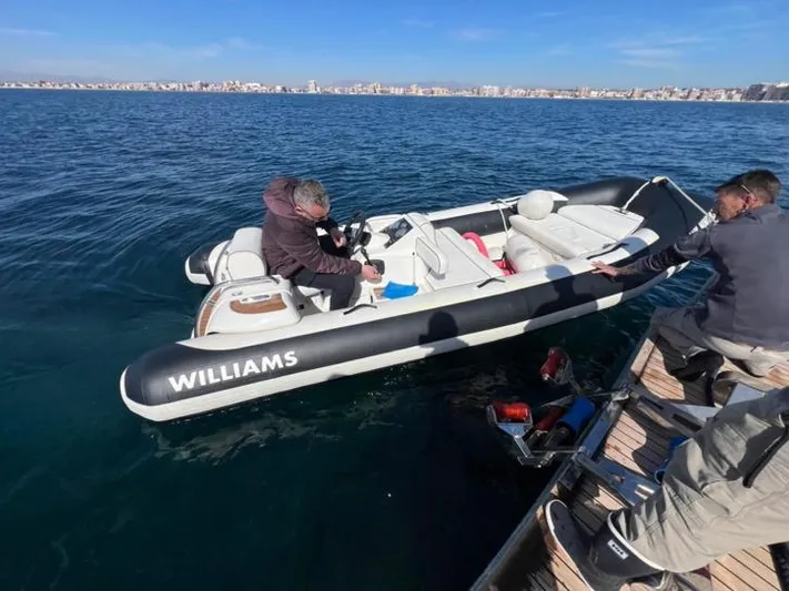 Armaar Yacht Photos Pics Small inflatable boat on water near dock, people boarding, clear sky, cityscape in background.