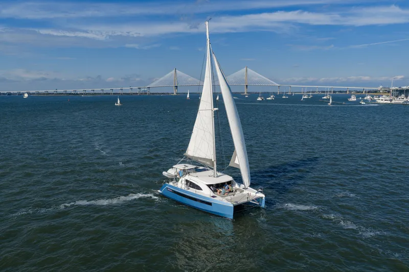 Everything Zen Yacht Photos Pics 2017 Leopard 40 catamaran sailing near a bridge on a sunny day.
