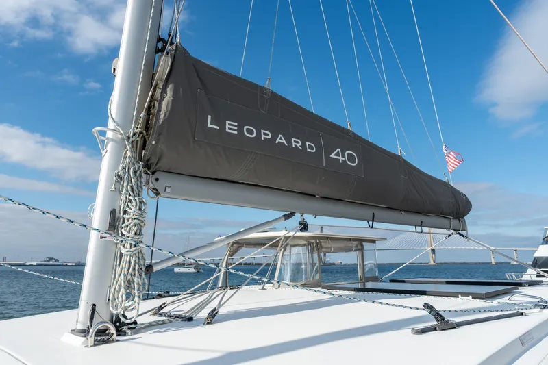 Everything Zen Yacht Photos Pics 2017 Leopard 40 catamaran with sail cover, docked near a bridge under blue sky.