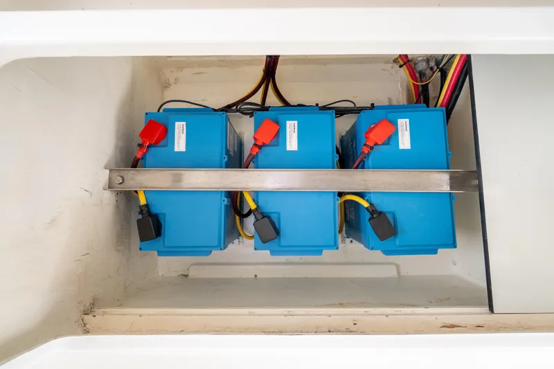 Everything Zen Yacht Photos Pics Blue batteries in a 2017 Leopard 40 yacht, secured with metal bar and connected with cables.