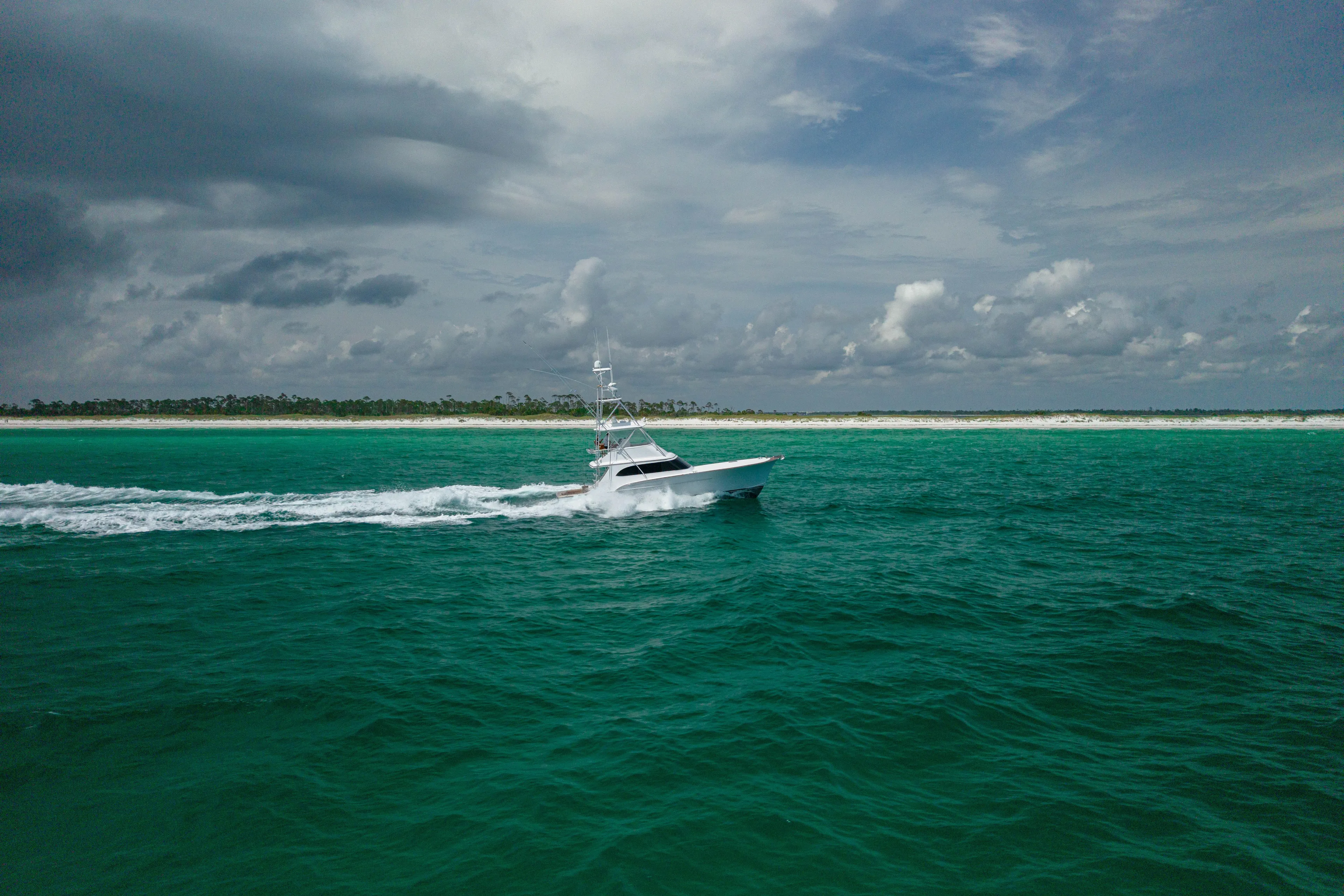 Honcho Yacht Photos Pics Custom Carolina Alex Willis Convertible 2000 cruising on turquoise ocean near sandy shoreline.