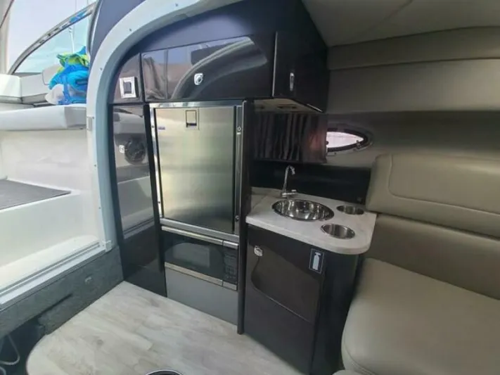  Yacht Photos Pics 2017 Formula 310SS boat interior with kitchenette, featuring a fridge, sink, and seating area.