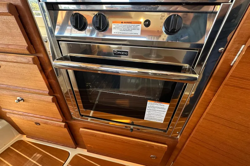Two For The Road II Yacht Photos Pics Stainless steel oven in 2020 Ranger Tugs R-29 boat kitchen, surrounded by wooden cabinetry.
